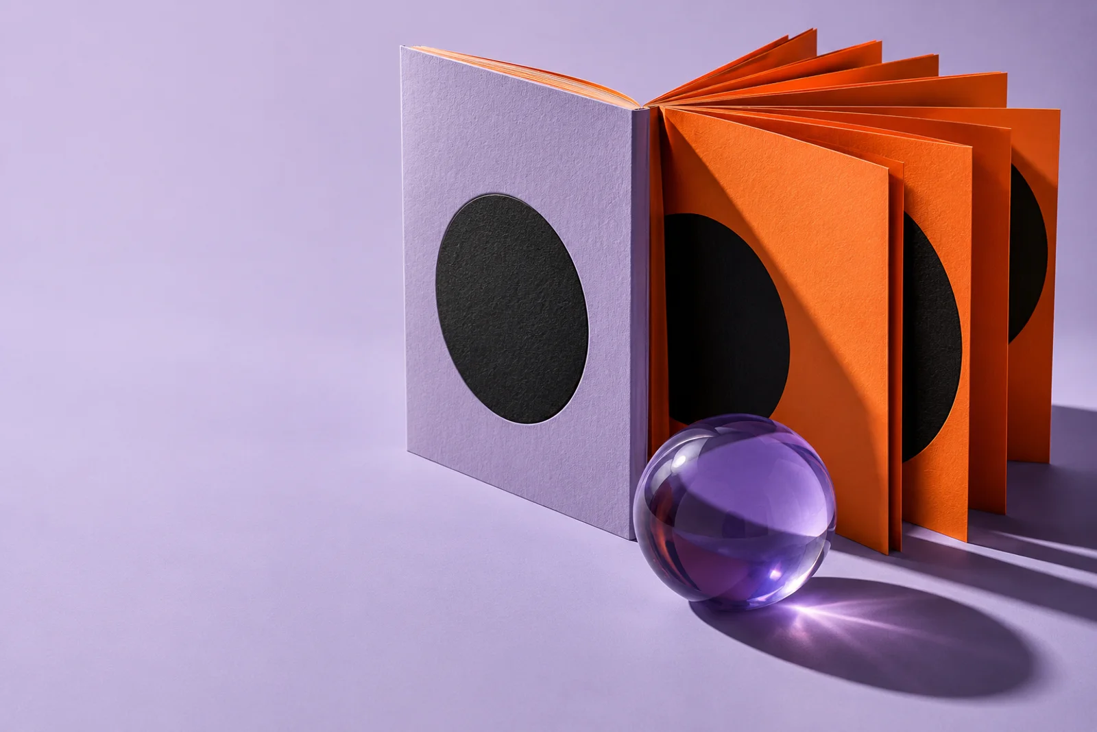 Libro conceptual lila con páginas naranjas y una esfera translúcida. Imagen generada.